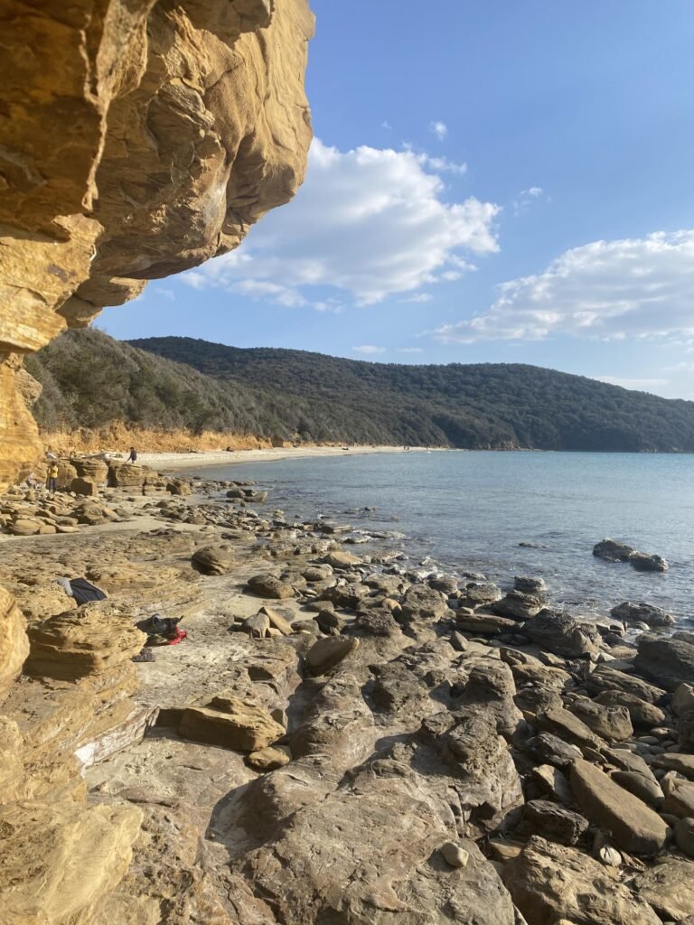 Spiaggia rocciosa di Calaviolina, mare cristallino e cielo limpido a Suvereto, perfetta per escursioni estive.