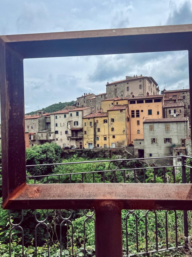 Vista panoramica di Sassetta, pittoresco borgo in Val di Cornia, incorniciato da un elemento metallico.