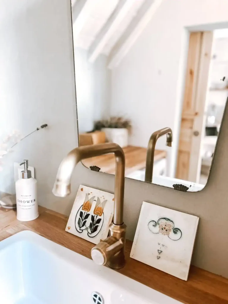 Rubinetto dorato in bagno elegante, casa vacanze Suvereto, Val di Cornia. Decorazioni e specchio riflesso.