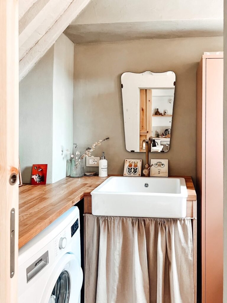 Bagno accogliente in casa vacanze Suvereto con lavabo, specchio vintage e lavatrice. Scopri Val di Cornia.