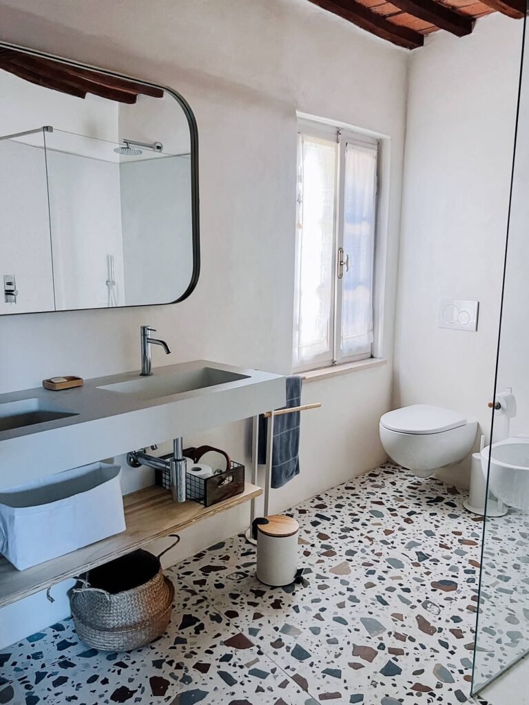 Bagno moderno con pavimento in terrazzo e arredi eleganti in una casa vacanze a Suvereto, Val di Cornia.