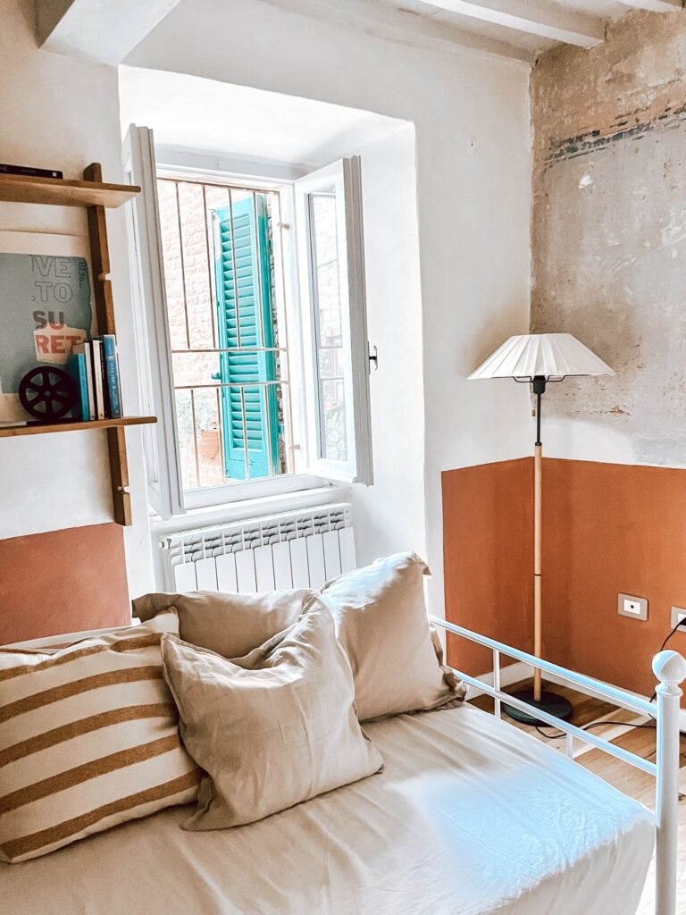 Interno luminoso casa vacanze Suvereto con finestra, cuscini e lampada, relax in Val di Cornia.