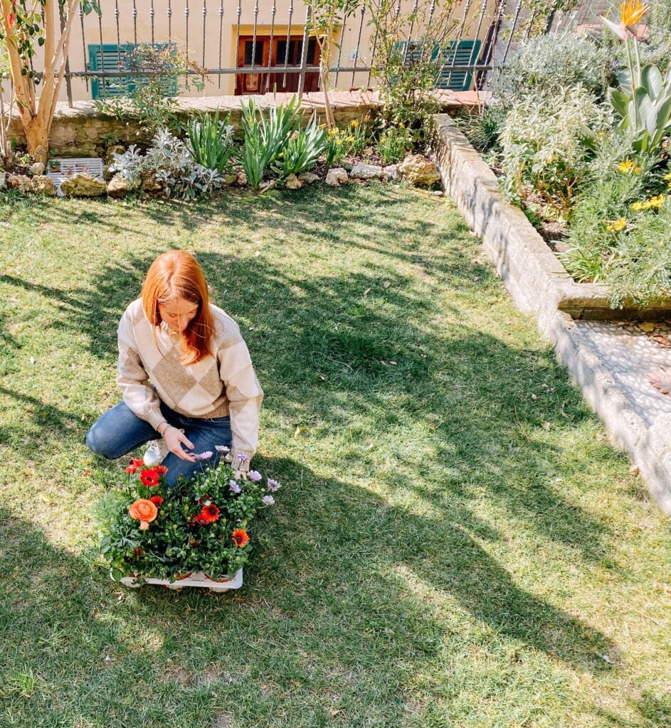 Donna in giardino curando fiori colorati, casa vacanze Suvereto, esperienza autentica Val di Cornia.
